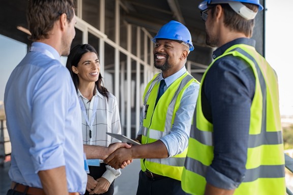 people shaking hands outside at construction site small